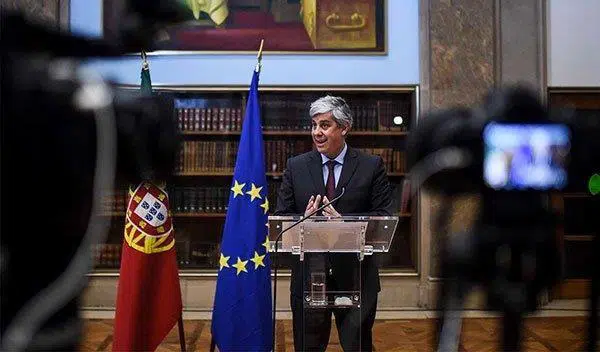 Ein Mann steht am Rednerpult neben einer EU-Flagge.